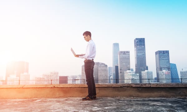 Man standing on a city roof with laptop